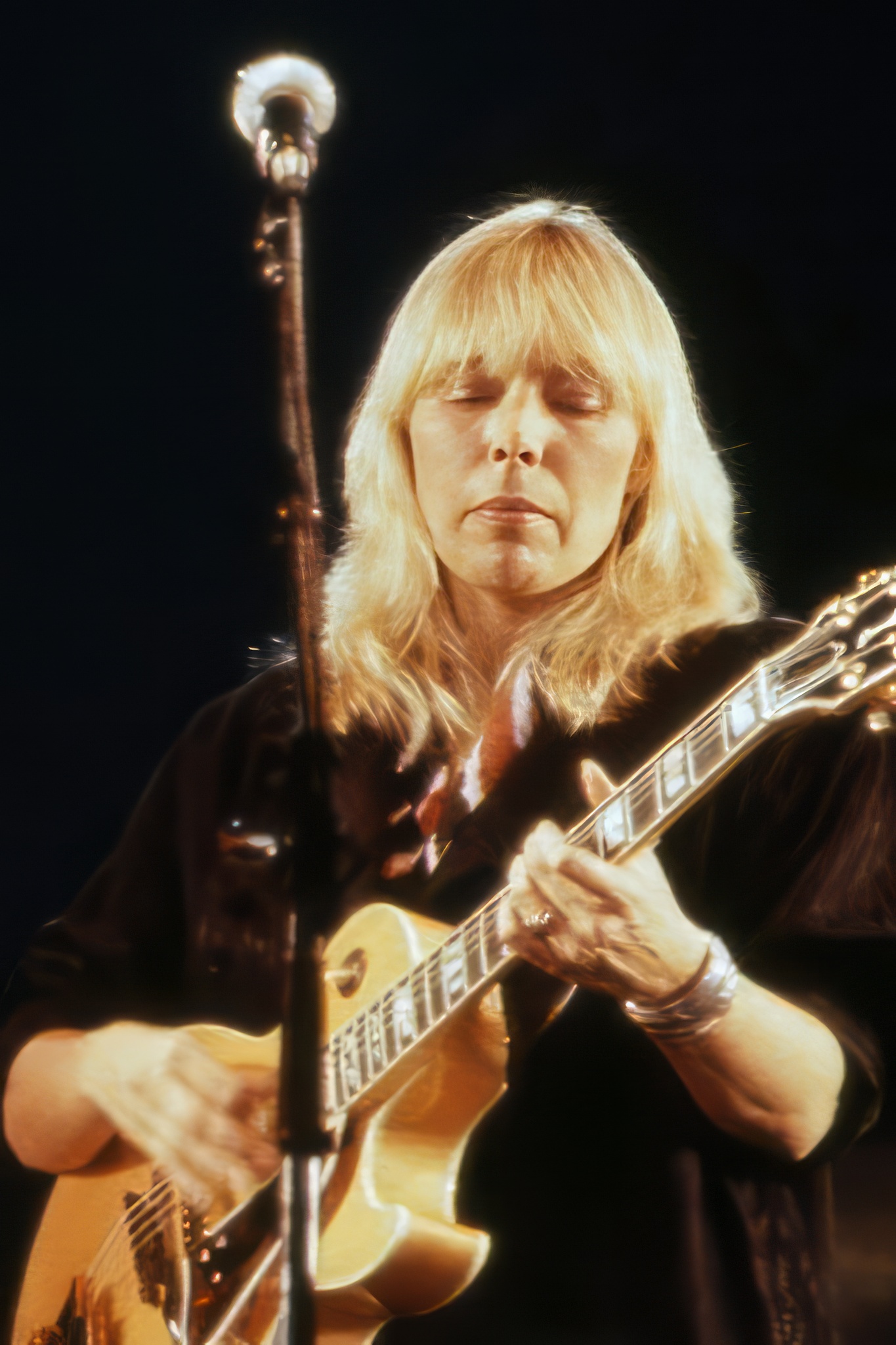 Joni Mitchell playing guitar at a concert in 1983.